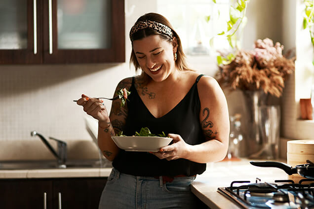 a women smiling and eating a nutritious bowl of food